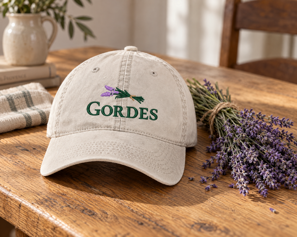 Cream Gordes cap with lavender embroidery beside lavender stems on a wooden table.